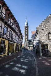 Deutschland, Niedersachsen, Goslar, Gasse in historischer Stadt mit Turm der Marktkirche St. Cosmas und Damian im Hintergrund - RUNF03465