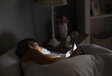 Frau schaut Film im Bett auf ihrem Tablet - VEGF00992