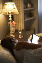 Woman reading a book in the bed on her tablet - VEGF00993