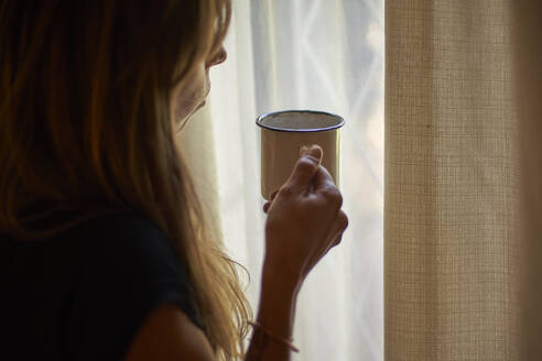 Woman having a cup of coffee in front of the window - VEGF00996