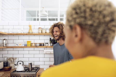 Lachender Mann mit Frau in der Küche zu Hause, lizenzfreies Stockfoto