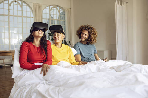 Glückliche Freunde haben Spaß mit VR-Brillen im Bett zu Hause - MCF00392