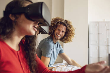 Glückliche Freunde haben Spaß mit VR-Brillen im Bett zu Hause - MCF00395