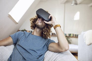Young man wearing VR glasses at home - MCF00405