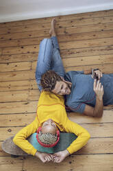 Young couple lying on the floor at home relaxing - MCF00413
