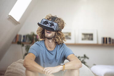 Young man wearing VR glasses at home - MCF00418