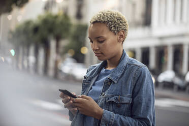 Junge Frau mit Smartphone in der Stadt - MCF00428