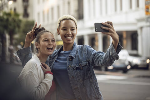 Zwei unbekümmerte junge Frauen machen ein Selfie in der Stadt, lizenzfreies Stockfoto