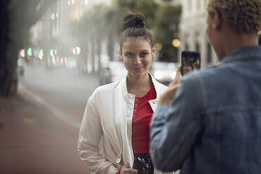 Junge Frau posiert für ein Smartphone-Foto in der Stadt - MCF00430