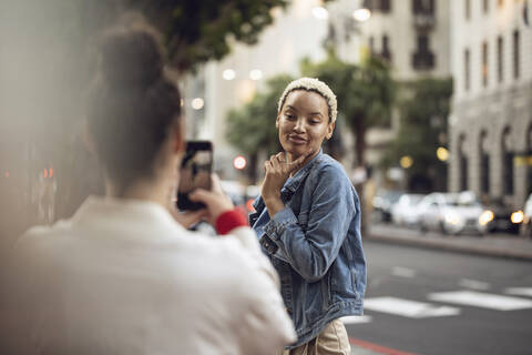 Junge Frau posiert für ein Smartphone-Foto in der Stadt, lizenzfreies Stockfoto