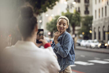 Junge Frau posiert für ein Smartphone-Foto in der Stadt - MCF00432