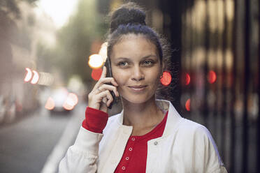 Porträt einer jungen Frau beim Telefonieren in der Stadt - MCF00436