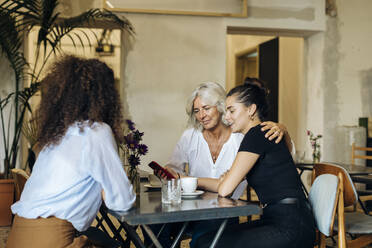 Frauen treffen sich in einem Bistro und schauen auf ihr Smartphone - SODF00422