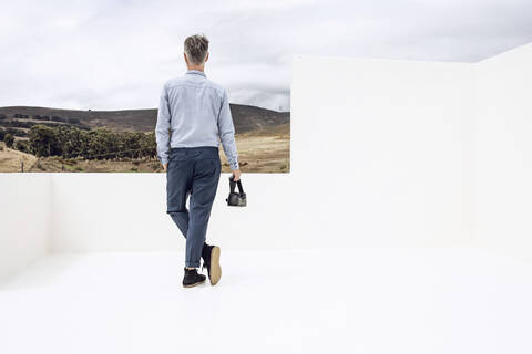 Älterer Mann mit VR-Brille, Blick in die Landschaft, Rückansicht, lizenzfreies Stockfoto