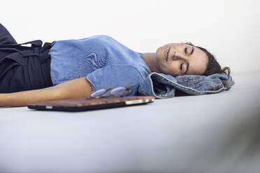 Young businesswoman taking a nap, lying on white wall - MCF00459
