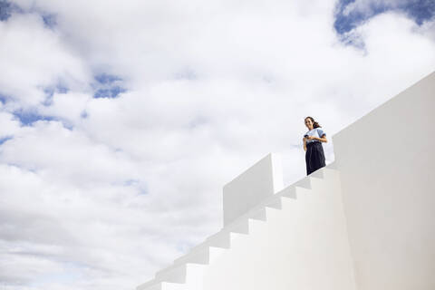 Geschäftsfrau, die auf einer weißen Treppe steht und ein Smartphone benutzt, lizenzfreies Stockfoto