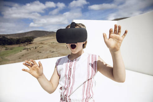 Girl looking through VR goggles in open space - MCF00508