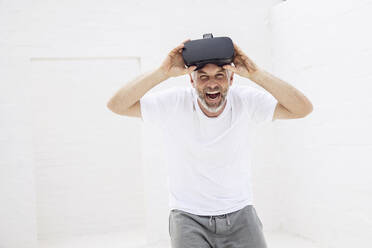 Mature man with VR goggles, looking at camera, laughing - MCF00521