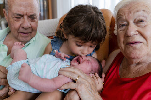 Großeltern mit kleinem Mädchen und neugeborenem Baby zu Hause, lizenzfreies Stockfoto