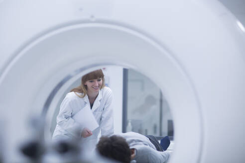 Patient im Krankenhaus während einer CT-Untersuchung, Radiologe lächelnd - SGF02470
