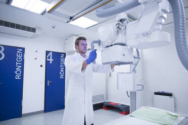 Radiologe beim Einstellen eines Röntgengeräts in einem Krankenhaus - SGF02480