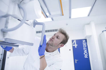 Radiologe beim Einstellen eines Röntgengeräts in einem Krankenhaus - SGF02483