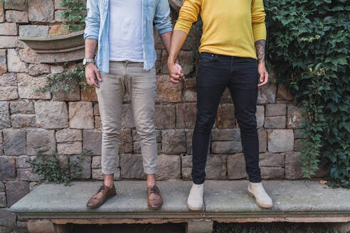 Crop-Ansicht eines schwulen Paares, das Hand in Hand auf einer Bank steht - AFVF04328