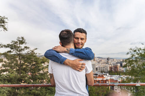 Porträt eines glücklichen Mannes, der seinen Freund umarmt, Barcelona, Spanien - AFVF04337