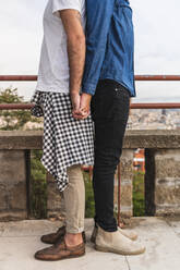 Crop-Ansicht eines schwulen Paares, das Rücken an Rücken steht und sich an den Händen hält, Barcelona, Spanien - AFVF04339