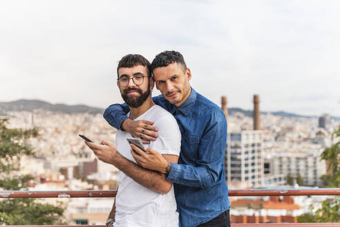 Porträt eines glücklichen schwulen Paares mit Smartphones, Barcelona, Spanien - AFVF04342