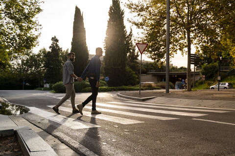 Schwules Paar überquert abends Hand in Hand die Straße, Barcelona, Spanien, lizenzfreies Stockfoto