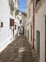 Italy, Province of Brindisi, Ostuni, Empty alley between old white-colored city houses - AMF07576