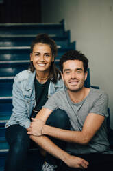 Porträt eines lächelnden Paares, das auf einer Treppe in einer Wohnung sitzt - MASF14756
