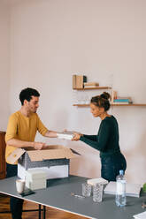 Mid adult couple unpacking books at new home - MASF14765