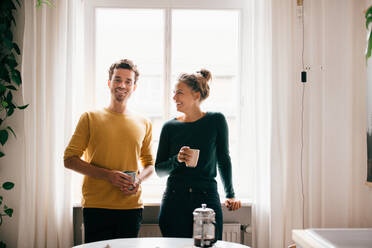 Glückliches Paar mit Kaffeetasse am Fenster zu Hause - MASF14771