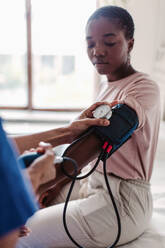 Abgeschnittene Hände einer Krankenschwester, die den Blutdruck eines jungen Patienten in einem Krankenzimmer überprüft - MASF14817