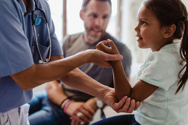 Mittelteil einer Krankenschwester, die ein Mädchen untersucht, das mit seinem Vater in einer Klinik sitzt - MASF14836