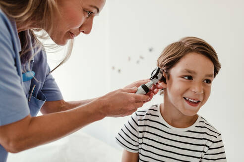 Arzt untersucht das Ohr eines Jungen mit einem Otoskop im medizinischen Untersuchungsraum - MASF14894
