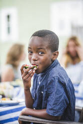 Porträt eines lächelnden Jungen, der auf einer Party im Garten eine Wassermelone isst - MASF14954