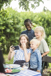 Mädchen nimmt Selfie mit Freunden auf Handy im Hinterhof - MASF14957