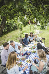 Hohe Winkel Ansicht von Freunden und Familie genießen am Esstisch im Garten Partei - MASF14968