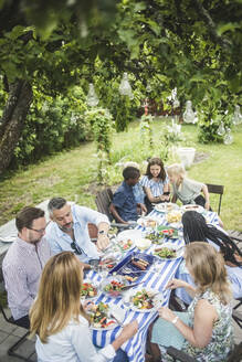 High angle view of friends and family enjoying at dining table in garden party - MASF14968