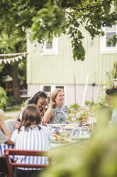 Familie und Freunde genießen das Essen, während sie am Tisch im Hinterhof zusammensitzen - MASF14973