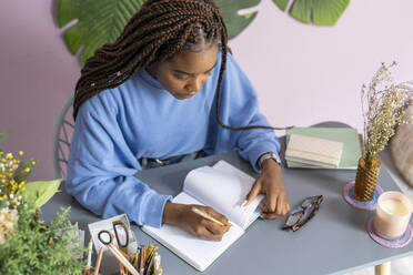 Young girl writing and working in her office - CAVF69512