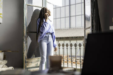 Girl talking on the phone on the balcony of her house - CAVF69518