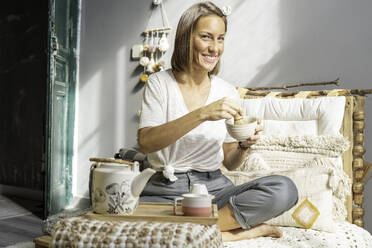 Girl preparing matcha tea in a traditional way on the sofa - CAVF69520