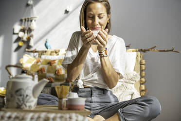 Girl having tea on the couch of her house - CAVF69522