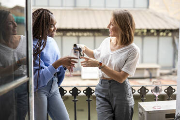 Couple of friends drinking wine on the balcony - CAVF69529