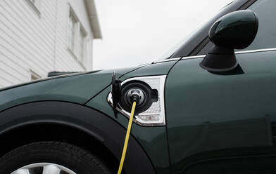 Electric car lead plugged into an electric car at home - CAVF69564