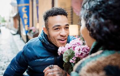 Portrait of a man looking at his girlfriend sat outside a cafe - CAVF69572